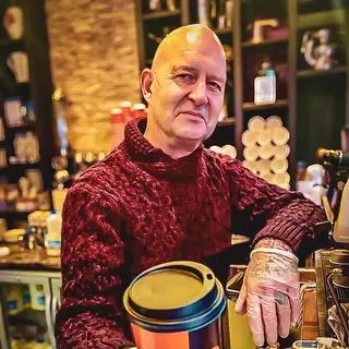 Buzz in a red jumper handing a takeaway cup across the counter