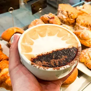 A cappuccino and a basket of bread photographed from directly above on a dark counter