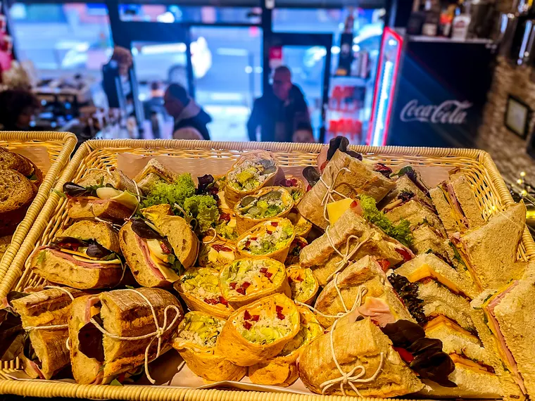 A wicker basket piled with sandwiches, wraps and tramezzini on the café counter, ready to go out to an office