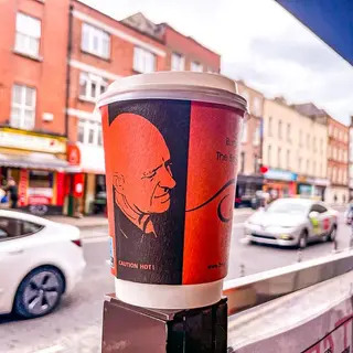 A takeaway cup on the window ledge with Dublin traffic passing behind