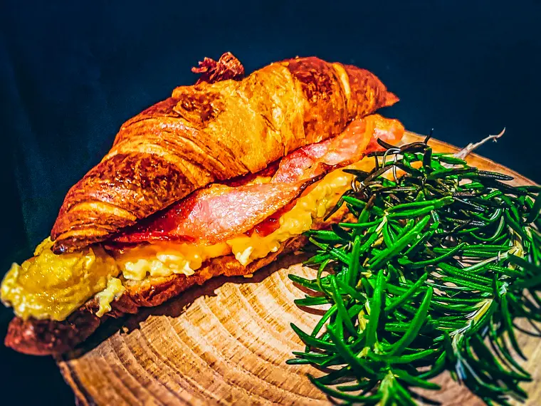 Golden croissant filled with scrambled eggs and crispy bacon