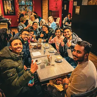 A table of guests giving a thumbs up over coffees and a slice of cake