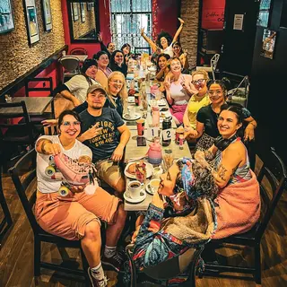 A large group filling the long table, waving at the camera