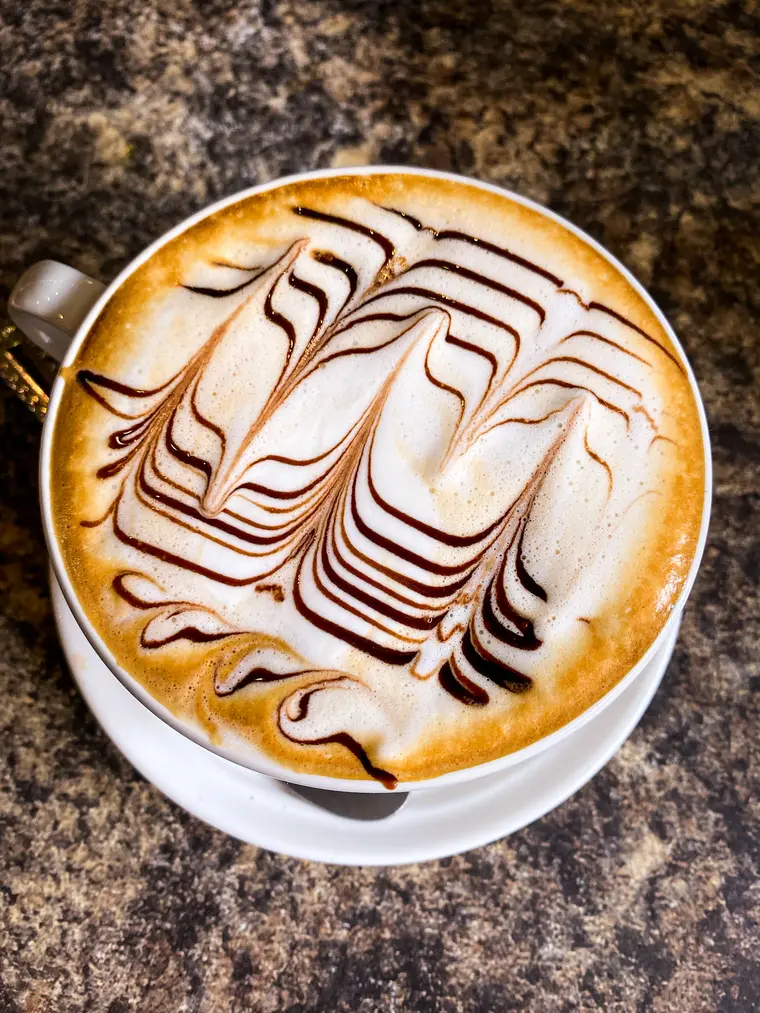Mocha in a white cup with a chocolate swirl drawn through the milk foam