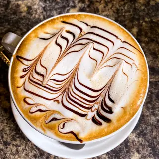 A mocha with a chocolate pattern drawn across the milk foam, seen from above