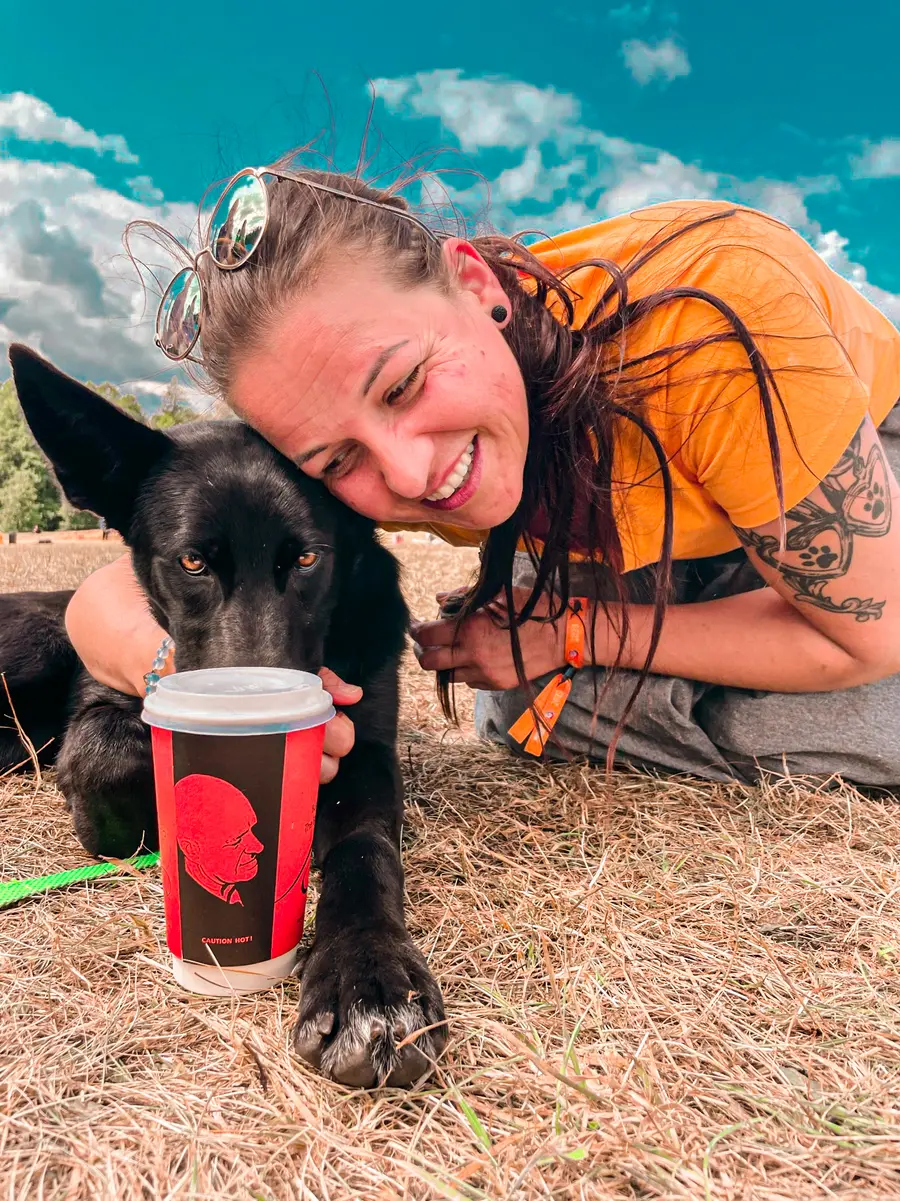 Monika outside with her dog and a Bald Barista takeaway cup