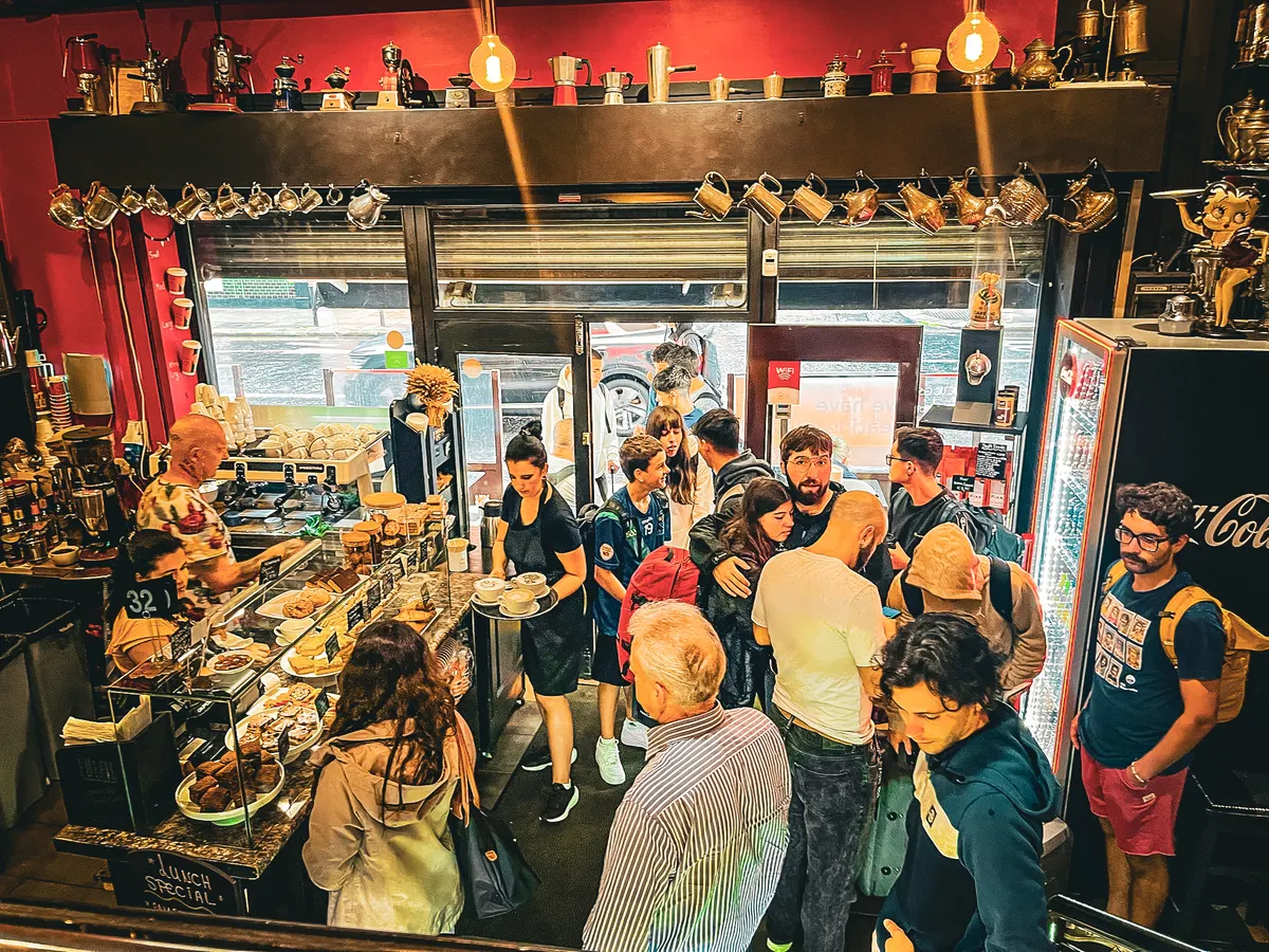 The glass display counter full of pastries and sandwiches, with customers waiting